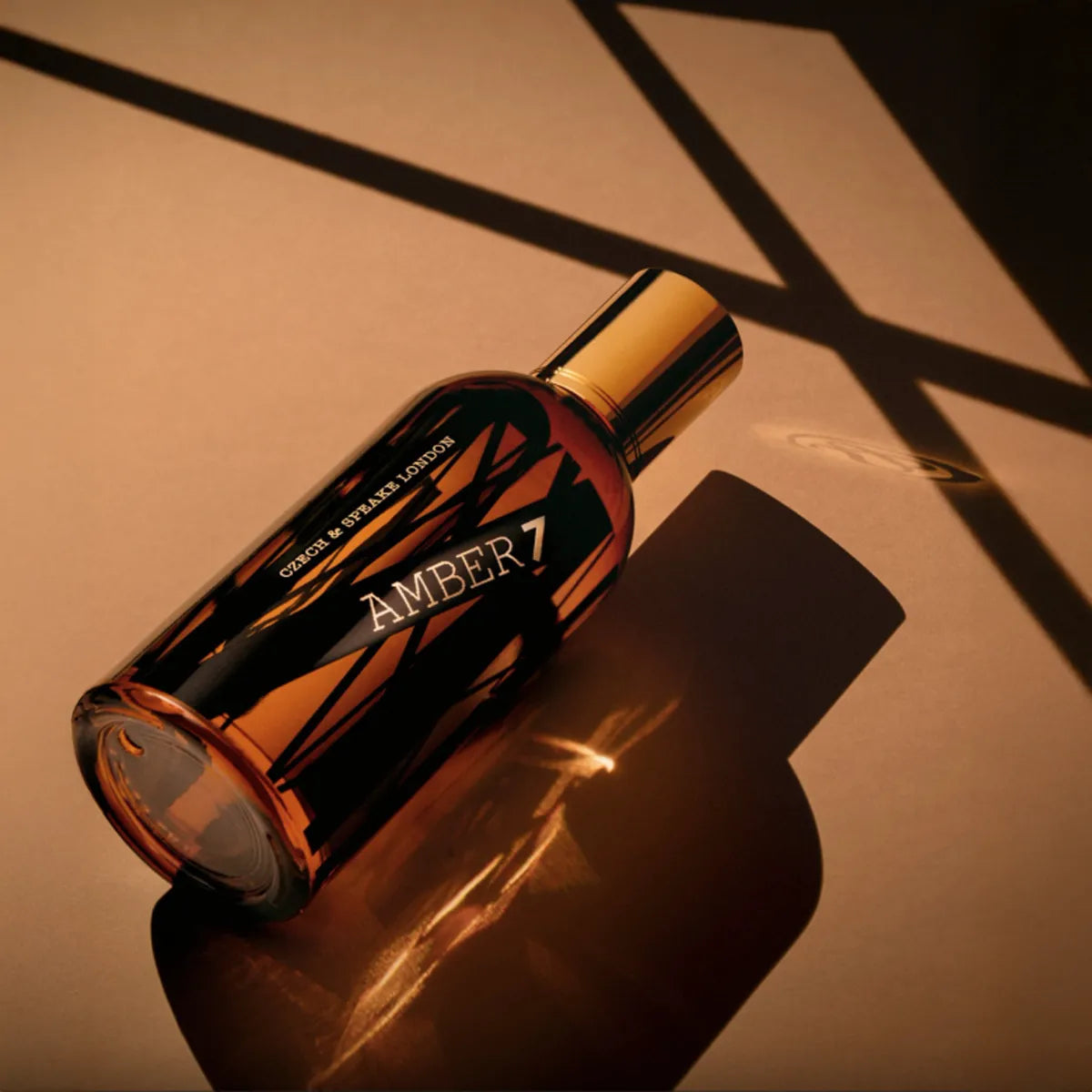 Perfume bottle labeled 'AMBER 7' on a reflective surface with warm lighting