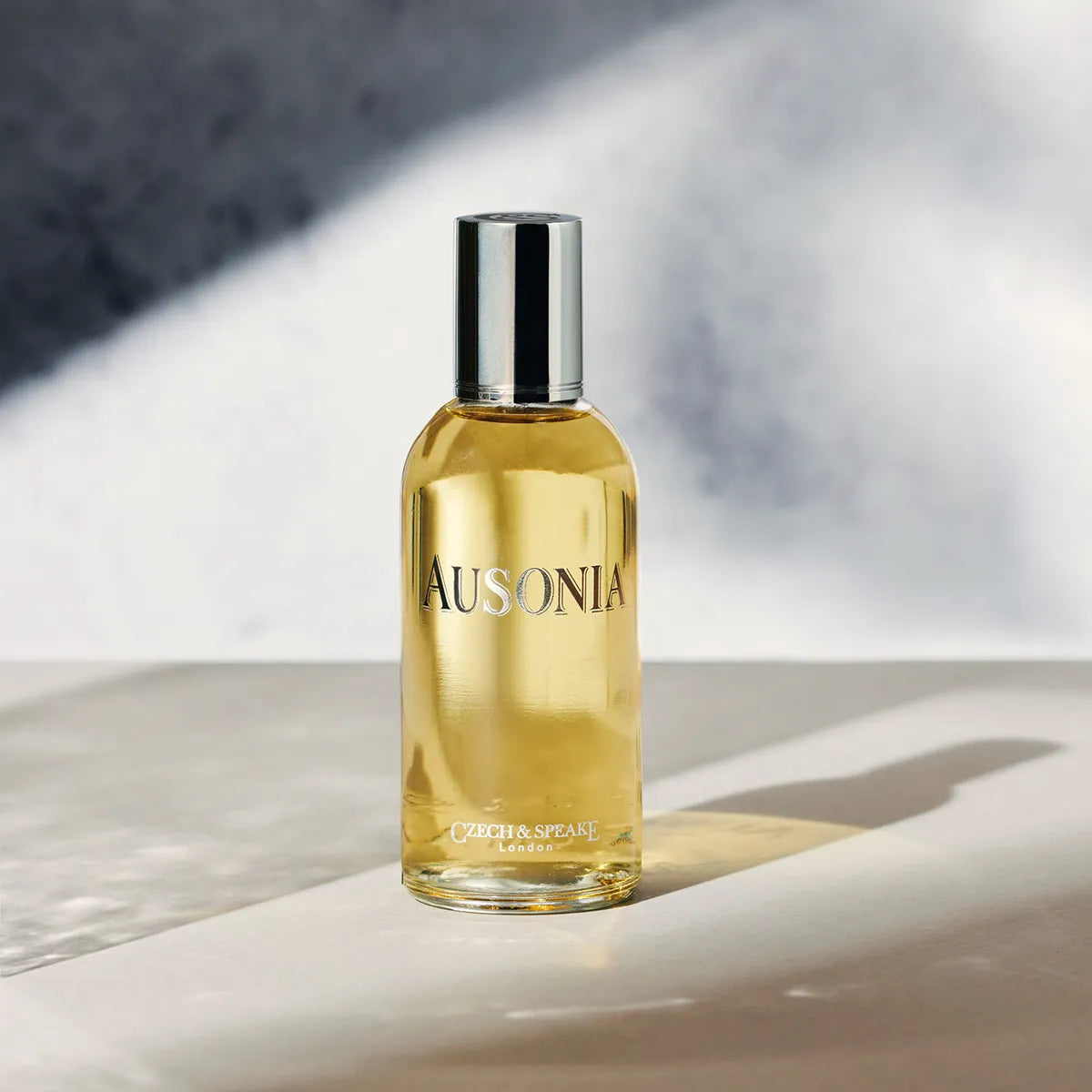 Bottle of Ausonia product on a reflective surface with a neutral background