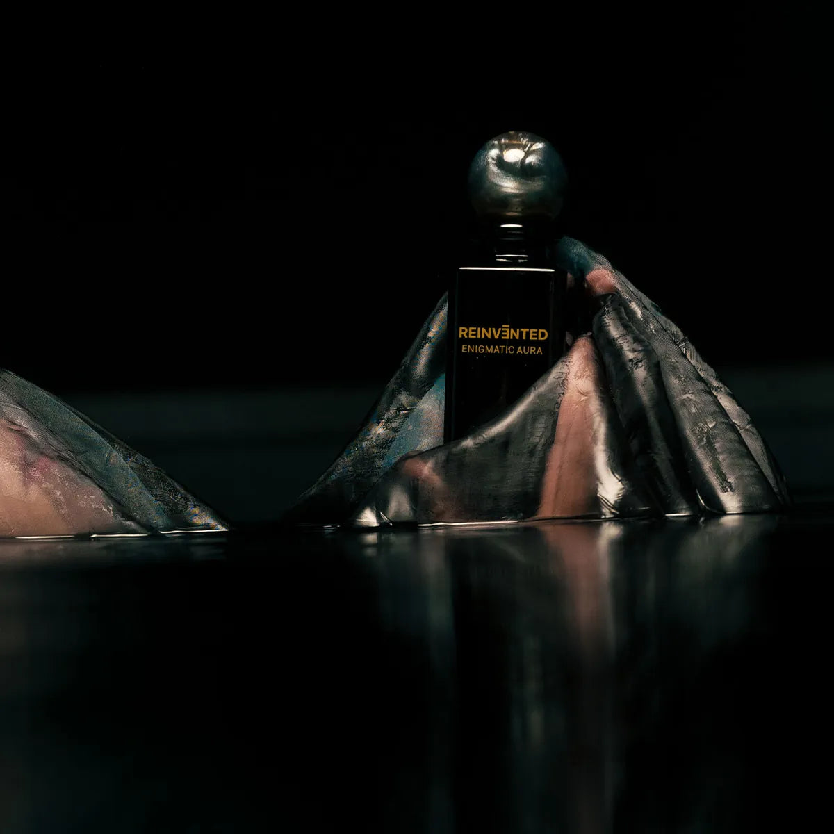Perfume bottle labeled 'Reinvented' on a dark background