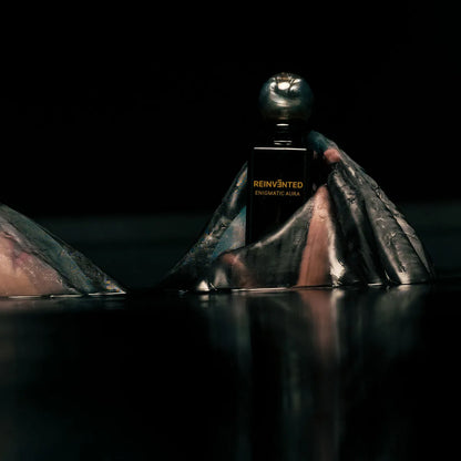 Perfume bottle labeled 'Reinvented' on a dark background