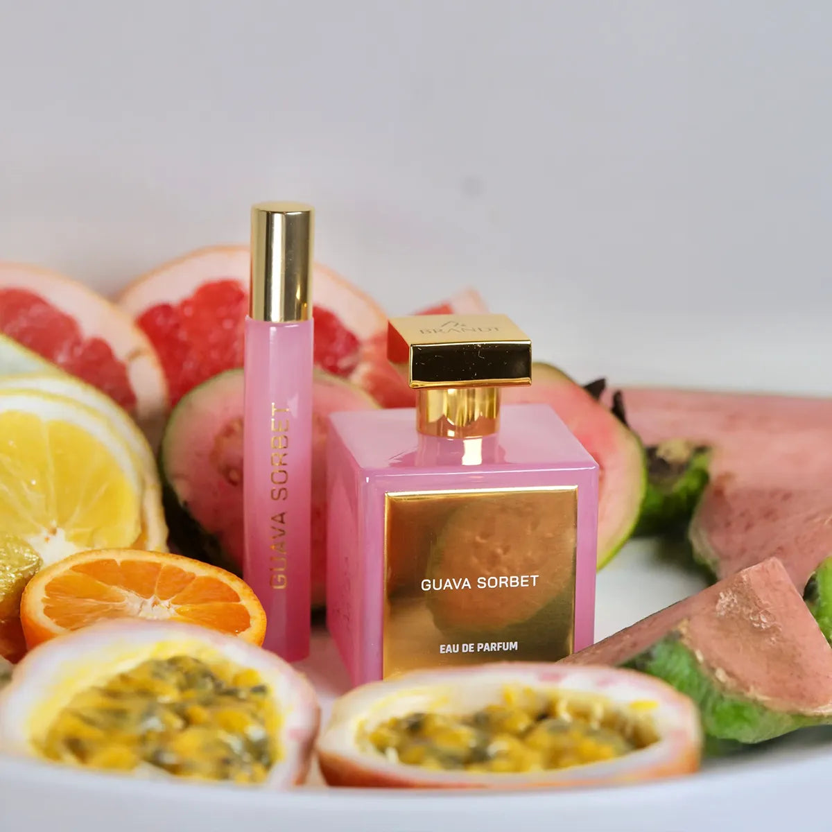 Pink and gold perfume bottles with fruit slices on a white background